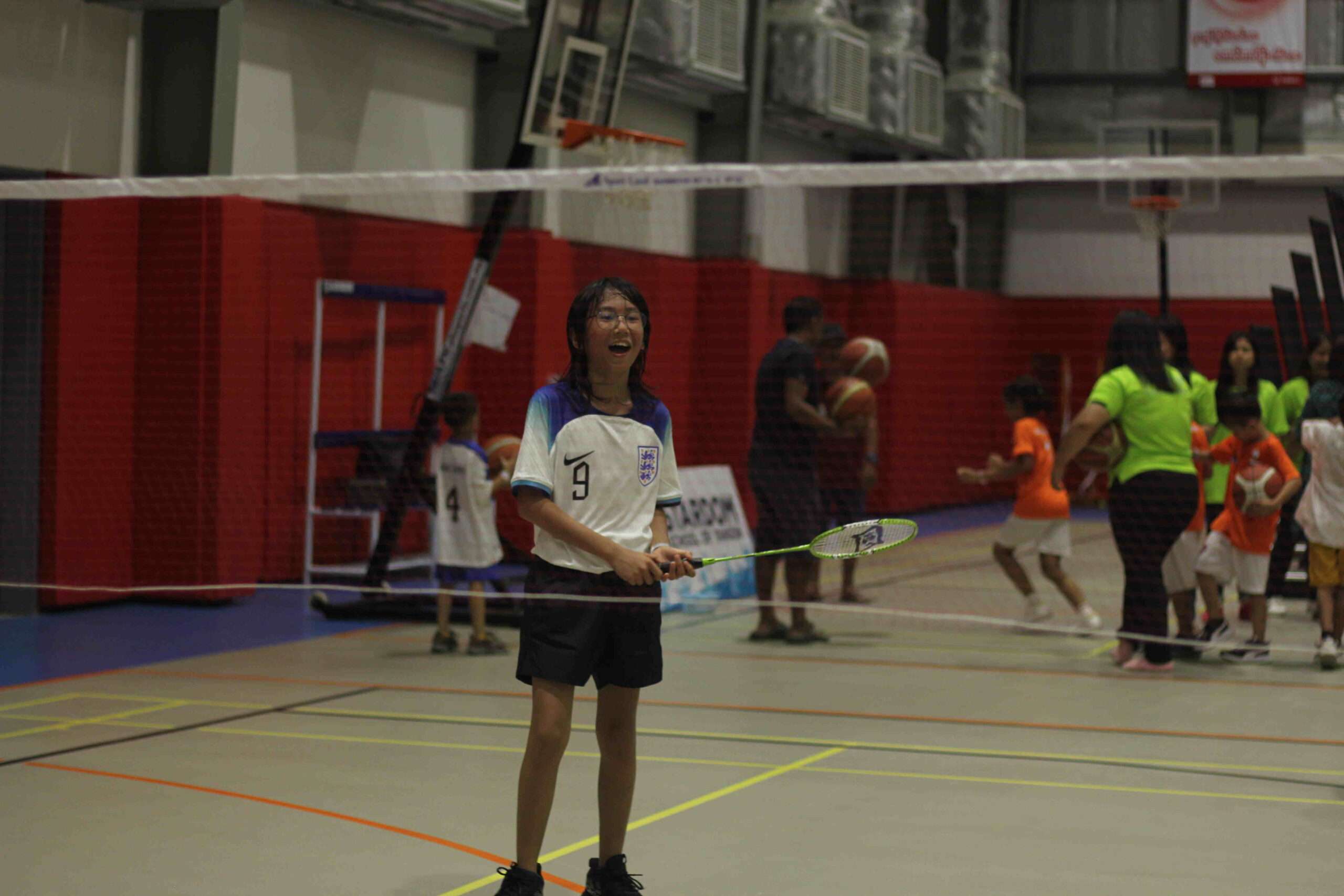 a girl holding a racket in a badminton court