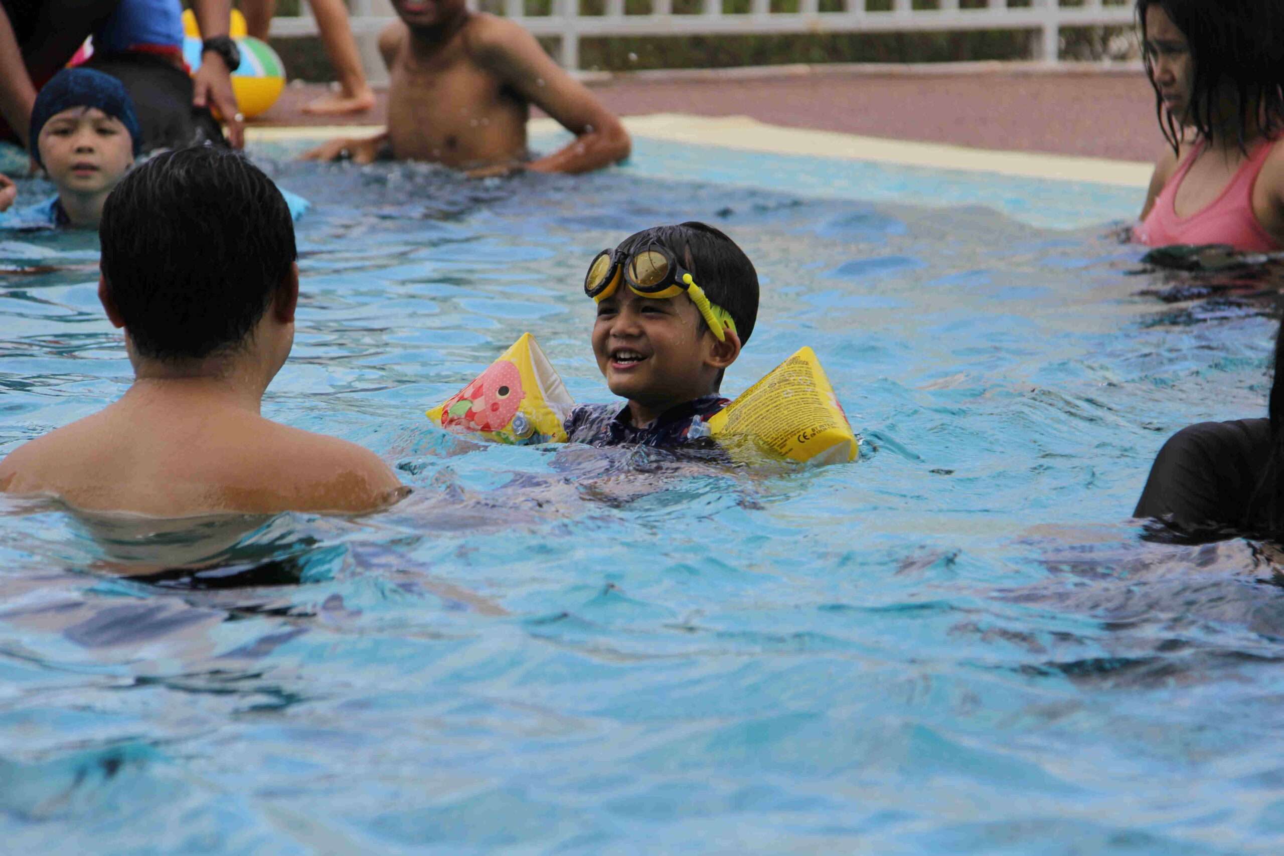 a child in a pool with goggles and a floater